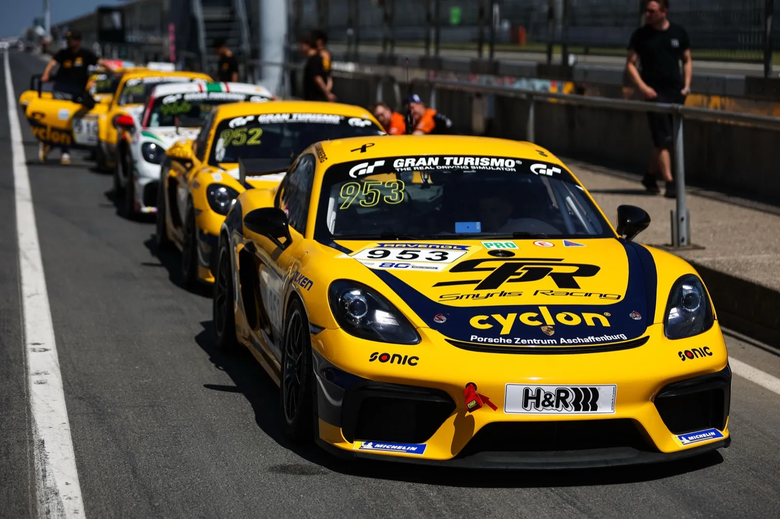 Gelber Porsche 718 Cayman GT4 mit Startnummer 953 von Smyrlis Racing in der Boxengasse