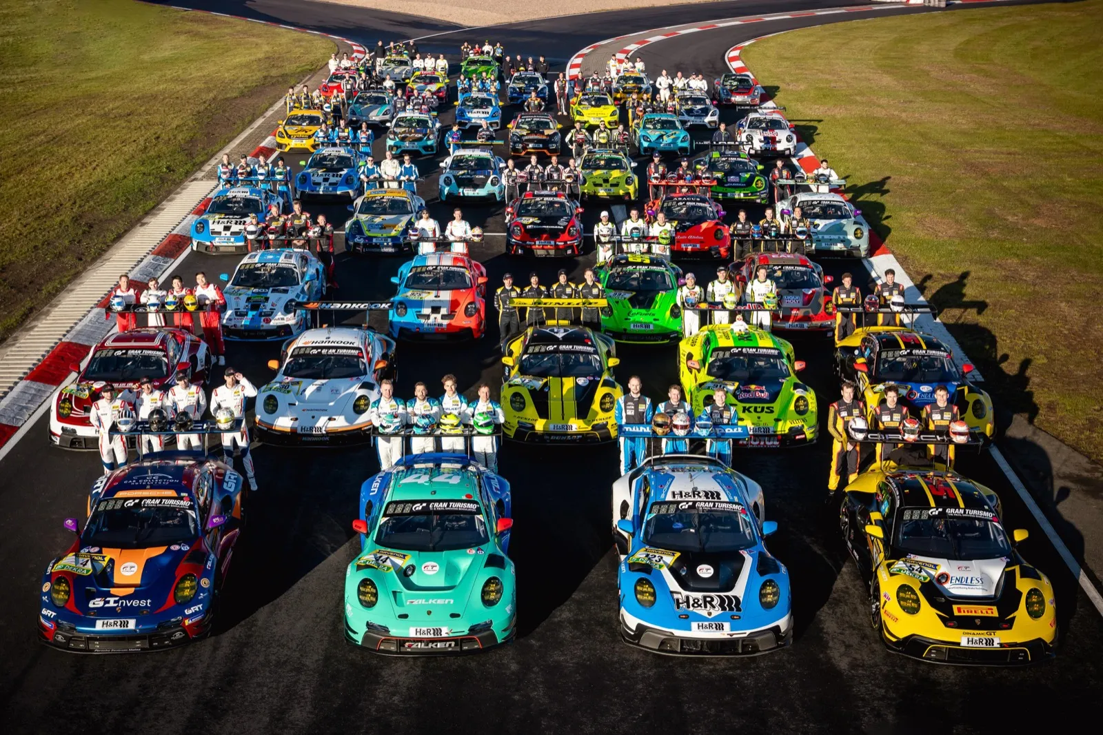 Gruppenfoto zahlreicher Porsche-Rennfahrzeuge und ihrer Fahrer auf der Rennstrecke